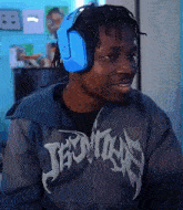 a man wearing headphones and a gray jacket with the word jesus on it