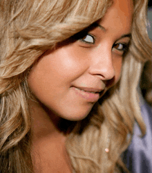 a close up of a woman 's face with a purple shirt in the background