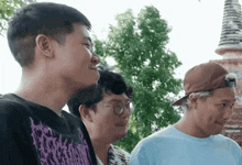 a man wearing a purple shirt with a skull on it is standing next to two other men
