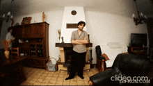 a man stands in front of a fireplace with his arms crossed in a living room