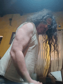 a man with long hair is wearing sunglasses and a tank top