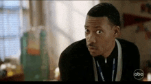 a man wearing a lanyard and a black jacket is looking at the camera .