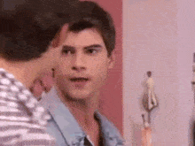 two men are standing next to each other in a room and one of them is looking at the camera .