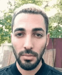 a man with a beard is wearing a black jacket .