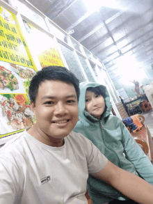 a man and a girl are posing for a picture in front of a yellow sign that says ' a ' on it