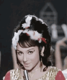 a woman is holding a microphone in her hand and wearing a headband of feathers in her hair .