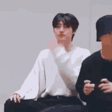 a man in a white sweater is sitting next to another man .