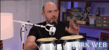 a bald man is playing drums in front of a microphone and the words dark web are on the bottom
