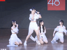 a group of girls are performing on a stage with the number 48 in the background