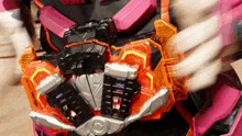 a person wearing a pink and orange robot costume is holding a toy .
