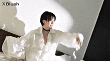 a young man in a white dress is sitting on a bed .