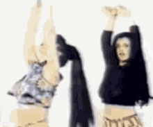 two women are dancing with their hands in the air