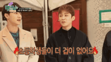 a group of young men are standing next to each other and one of them is talking in korean .