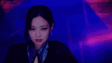 a close up of a woman 's face in a dark room with a blue and pink background .