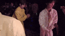 a man in a yellow jacket is standing next to another man in a pink jacket .