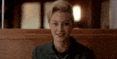 a woman is smiling while sitting in a chair in a restaurant .