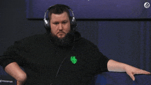 a man wearing headphones and a black shirt with a green logo on the front