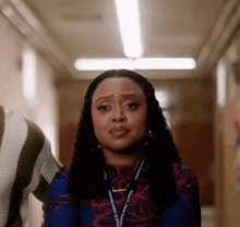 a woman is standing in a hallway with her eyes closed and a necklace around her neck .