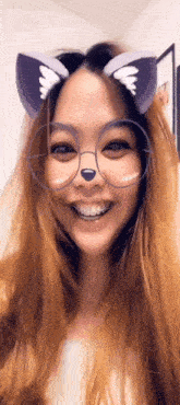 a woman wearing cat ears and glasses smiles for the camera .