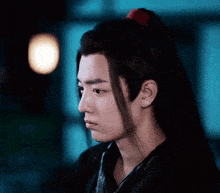 a close up of a young man 's face with long hair and a red ponytail .