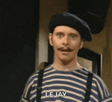 a man with a mustache and a beret is wearing a striped shirt and suspenders and says lejay .