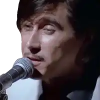 a close up of a man singing into a microphone with his eyes closed