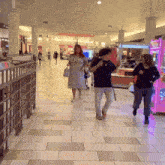 people walking in a mall with a pink claw machine
