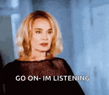 a woman in a black dress is saying go on-im listening
