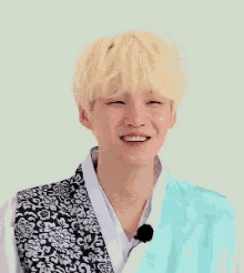 a young man with blonde hair is smiling while wearing a kimono and a microphone .