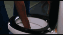 a person is standing in a toilet with their legs in the toilet seat .