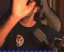 a man in a black shirt is standing in front of a microphone and making a funny face .