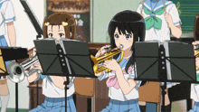 a girl playing a trumpet while another girl looks on
