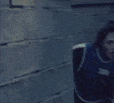 a man is running in a dark room wearing a blue shirt with the number 360 on it .