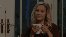 a woman is smiling while holding a mug that says ' a ' on it