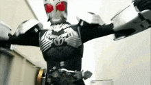 a man in a masked superhero costume is standing in a room with his arms outstretched .