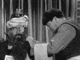 a man with a beard is being shaved by another man in a turban