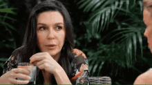 a woman holds a glass of water in her hand while talking to another woman