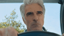 a man with gray hair is driving a car