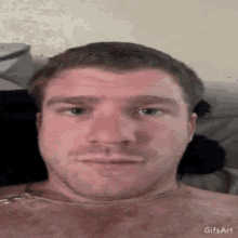 a man without a shirt is laying on a bed with a gif art watermark