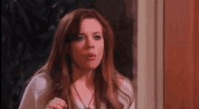 a woman is standing in front of a window with her mouth open and making a funny face .