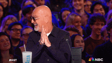 a man sitting in front of a crowd with a nbc logo on the bottom