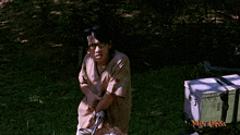 a man is standing in the grass with a man laksa logo on the bottom