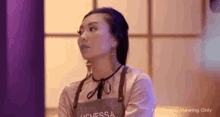 a woman in an apron is sitting in front of a purple wall .