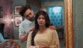 a man is comforting a woman in front of a mirror in a bedroom .