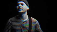 a man in a striped shirt is playing a guitar in a blurry photo .