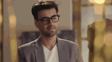 a man with glasses and a beard is wearing a suit and a white shirt