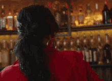 a woman wearing hoop earrings is sitting in front of a bar