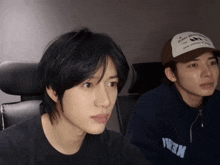 two young men are sitting next to each other and one of them is wearing a baseball cap that says ' army '