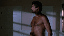 a shirtless man stands in front of a door in a room