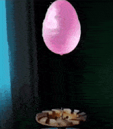 a pink balloon is being blown up by a needle on a table .